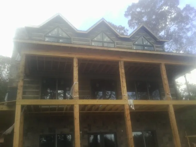 Dormers and porch framing on a large log home under construction — Roof Coating work by our crew in Blodgett Mills