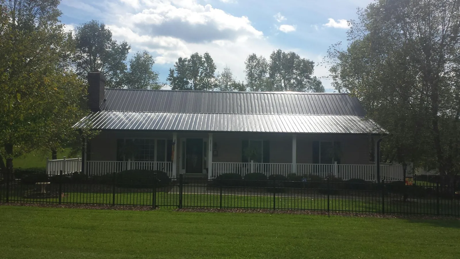 Gray metal roof on a brick ranch with a full width front porch — Gutter Guard Installation work by our crew in Blodgett Mills