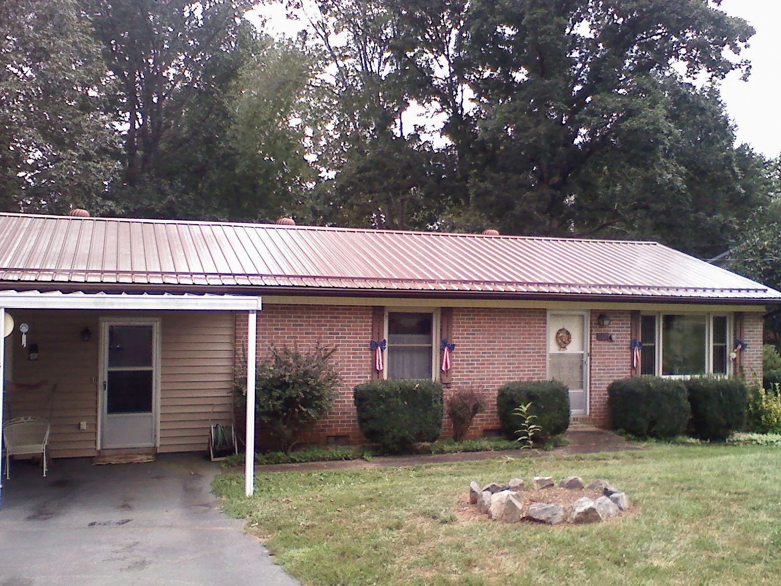 Bronze metal roof and carport on a brick ranch home — Roof Repair work by our crew in Blodgett Mills