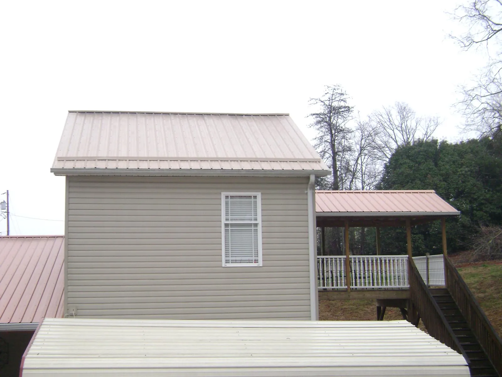 Tan metal roofs on a two story addition and attached porch, from a Roof Replacement job in Blodgett Mills