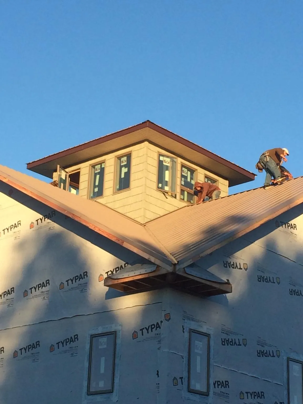 Roofers working around a rooftop cupola on a new metal roof at sunset — Roof Waterproofing in Blodgett Mills by Roofing Brothers